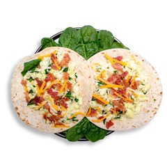 An overhead view of a nutritious breakfast taco plate showcasing two open tortillas topped with fluffy egg whites blended with wilted spinach, savory bacon crumbles, and a colorful blend of shredded cheddar and pepper jack cheese. This balanced and satisfying healthy meal prep option blends protein, greens, and a touch of indulgence for those seeking flavorful health food without compromise.