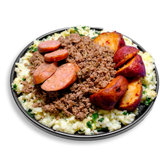 A 3/4 view of a high-protein healthy prepared meal featuring seasoned lean ground turkey layered over fluffy scrambled egg whites with spinach. Surrounding the center are roasted red potatoes with crispy, golden-brown skins, and thick slices of smoky bison jalapeño cheddar sausage. This hearty health food plate delivers balanced macros perfect for healthy meal prep and fueling active lifestyles.