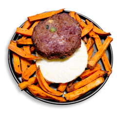 A hearty and colorful healthy prepared meal featuring a seared ground bison patty perched atop a perfectly round egg white medallion, surrounded by a generous serving of roasted sweet potato fries. Flecked with green onion and celery, and seasoned with a bold blend of roasted garlic, cumin, and Creole spices, this high-protein dish delivers balanced fuel for any time of day.