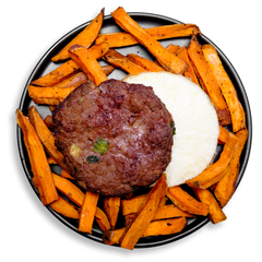 This bold and savory healthy meal prep plate features a thick, hand-formed bison burger studded with herbs and vegetables, set atop a circular bed of egg white. Surrounding the centerpiece is a ring of vibrant, roasted sweet potato fries seasoned with garlic, Worcestershire, and Creole spices. A flavorful and nutrient-rich meal designed for clean eating and sustained energy.