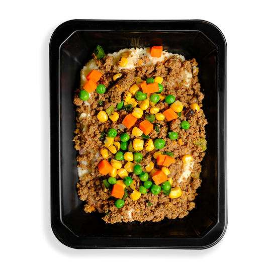 A hearty to-go meal with lean ground bison, red potatoes, and mixed vegetables like peas, carrots, cauliflower, and corn, all coated in a rich, creamy parmesan and garlic sauce. A healthy twist on the classic British dish is what this looks like to me. The togo container appears to be designed for people who have food delivered or want to pick up healthy food in a store and are too busy to cook.