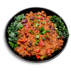 A hearty, healthy prepared meal featuring a spicy, protein-packed chili made with lean ground turkey and black beans. The vibrant chili mixture is richly colored with fire-roasted tomatoes, red and green bell peppers, and dotted with chunks of celery and red onion. It’s served atop a bed of fresh curly kale and garnished with sliced green onions for a fresh, crisp finish. Perfect for health food lovers looking for a bold, flavorful meal prep option with a nutritious twist.