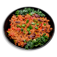 A colorful, wholesome plate of chili crafted for clean eating—featuring a savory blend of lean turkey, black beans, and vegetables simmered in a spiced tomato base. The chili is rich with textures from chopped bell peppers, celery, and onions, all spiced with cumin, cayenne, and pink Himalayan sea salt. Fresh kale frames the dish, adding a pop of green and an extra nutrient boost. A satisfying, spicy healthy prepared meal ideal for meal preppers and chili enthusiasts alike.