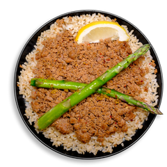 A black meal prep container filled with a nutritious combination of finely crumbled lean ground turkey seasoned with pink Himalayan sea salt, garlic powder, and cayenne, layered over hearty brown rice. Bright green asparagus spears cross at the center, adding contrast and crunch, while a juicy lemon wedge hints at the zesty undertones in this bold and flavorful healthy meal prep dish.