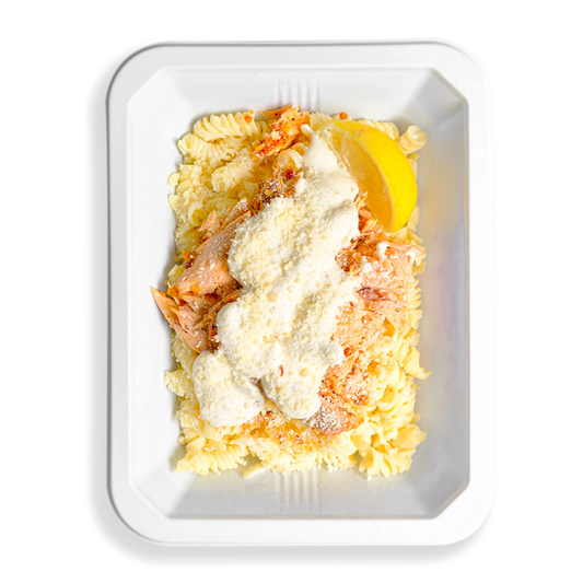 Light-colored dish of shredded roasted salmon on gluten-free pasta, coated in a house-made Alfredo and parmesan blend, softly filling the white to-go tray with creamy comfort.  But comfort aside this looks like the perfect health meal that is prepared for people who love eating clean and are too busy to always be cooking.