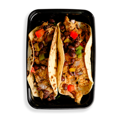 Two loaded up chicken tacos fill a black to-go container.  The flour tortillas are stuffed with a seasoned pulled chicken and topped with beans and peppers.  This food looks delicious and because it is served in a to-go container communicates to me that this is a prepared meal for delivery or pickup. 