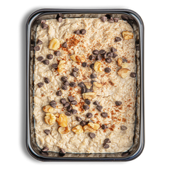 A mash of beige oats fill this reflective togo container.  On top of this food I see chocolate chips and what look like some type of nut.  This looks like the definition of a robust and hearty breakfast for anyone looking to start their day off on a good foot.